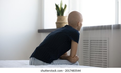 Rear Back View Stressed Young Hairless After Chemotherapy Woman Sitting On Bed Looking In Distance, Thinking Of Oncology Treatment Or Operation, Feeling Depressed Alone Indoors, Cancer Fight Concept.