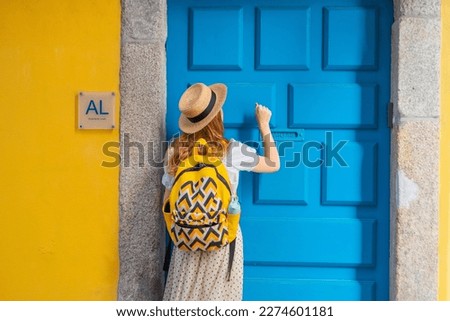 Rear back view of young tourist woman knocking the door of the AL - Alojamento local - typical accommodation in Portugal. enjoying a vacation in Europe.