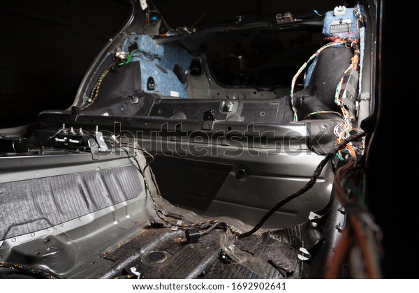 The rear body interior part of the cabin inside\
the sedan car, dismantled trim with colored wires, prepared for the\
replacement and installation of noise insulation in auto service\
for tuning vehicles