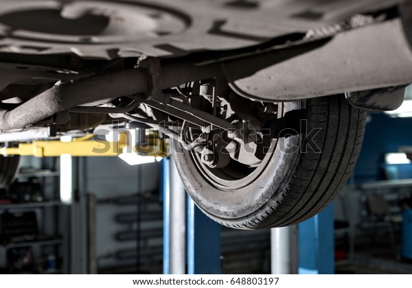 rear car suspension. the garage mechanic raised the\
car on the lift