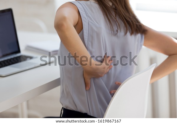 Rear close up view girl touch back feels\
unhealthy by uncomfortable office chair increase backpain.\
Sedentary work, wrong posture incorrect position, intervertebral\
disc, spinal joint damage\
concept