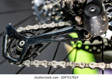 The Rear Derailleur Of A Mountain Bike Is A Close-up On A Black Background. Mountain Bike Repair In The Workshop. Dirty Mountain Bike After The Competition.