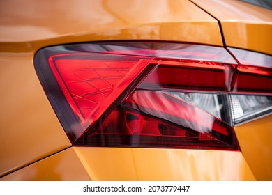 Rear edgy red LED light. Taillight of orange car. Close up. Logo Retouched.