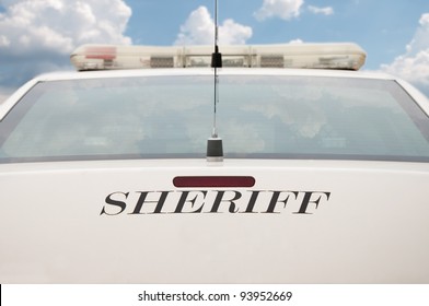 Rear End Of A Sheriff's Patrol Car With Cloudy Sky Background