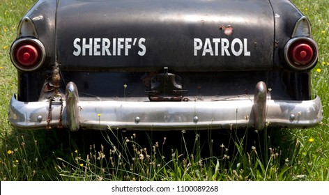 Rear End Of Vintage Antique Sheriff's Black And White Patrol Car In Field.