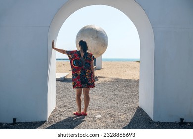 Rear of hipster woman with colorful dress standing on gate and look at artificial moon and sea background. - Powered by Shutterstock