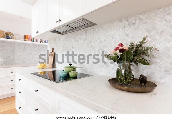 Rear kitchen bench styled with cut flowers and\
colorful saucepans