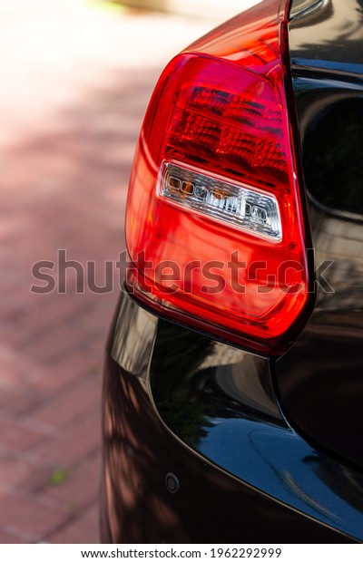 Rear left headlight car close up. red\
turn indicator of a black luxury automobile in a parking lot.\
Modern car rear lights that shine brightly\
outdoors.