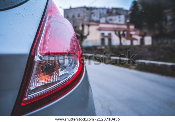 Rear light of a subcompact car in the rain, in\
winter, italy
