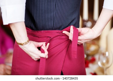 Rear midsection of waitress tying apron in restaurant - Powered by Shutterstock