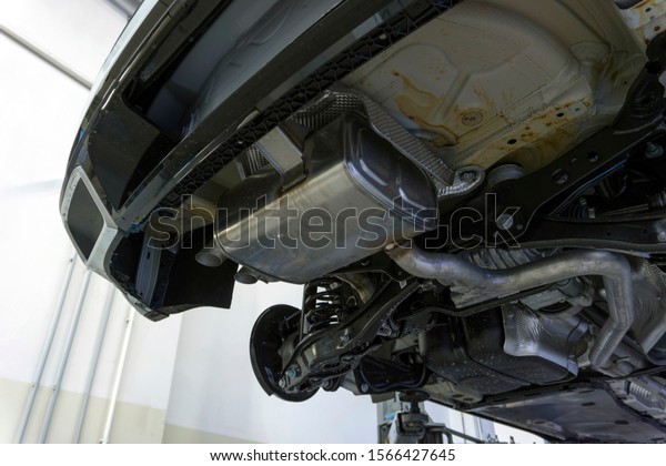 The rear muffler of a\
modern car and part of the exhaust system. The car is raised on a\
lift. Diagnostics and service of the car. Original spare parts for\
the car.