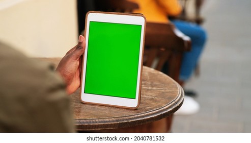 Rear of multiracial male looking at tablet with chroma key while sitting at the cafe at the street. Guy looking at device with green screen. Close up 