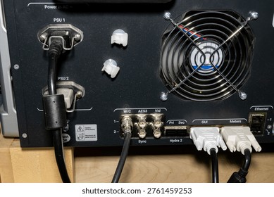 rear panel of electronic device with power and data connections
--
close up view of the rear side of an electronic device showing power supply units, cooling fan, and multiple connected cables. visible connectors include power inputs, data ports, and network interfaces. the image represents professional technology equipment, hardware infrastructure, data systems, and technical installations in an indoor environment