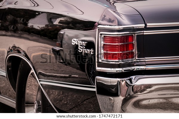 Rear\
part of exterior of a black old timer luxury sports car with tail\
lights in chrome frames and shiny chrome\
bumper.