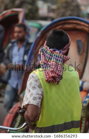 Rear photo of a rickshaw puller in a busy street of Bangladesh.Rickshaw puller with rickshaw is searching for passenger.Due to coronavirus outbreak,its became  very hard for them to living