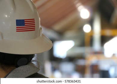 Rear Portrait Photo Behind A Female Construction Worker On A Building Job Site. American Flag On Back Of Her White Hard Hat. Woman Foreman In Charge Of Successful Development Team.