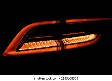 Rear Red Car LED Lights In The Dark. Bright Modern Car Headlights On A Black Background. Background Bright Red LED Car Taillights In The Dark. Overhead Light Diodes Isolated On A Black Background.