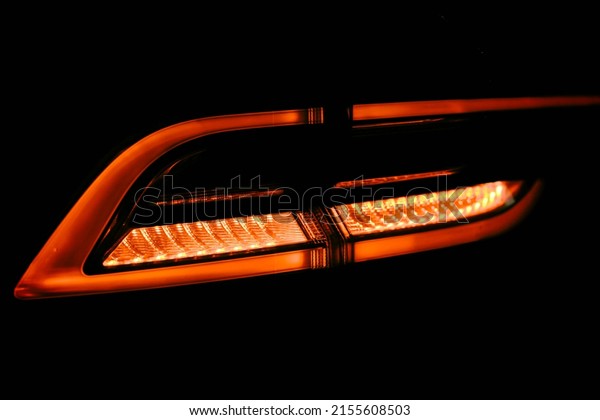 Rear red car LED lights in the dark. Bright\
modern car headlights on a black background. Background bright red\
LED car taillights in the dark. Overhead light diodes isolated on a\
black background.