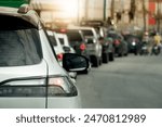 Rear side of car on the asphalt road. Cars parked in a long queue in a curve. Traffic jam in the evening time. City for background with light of sun.