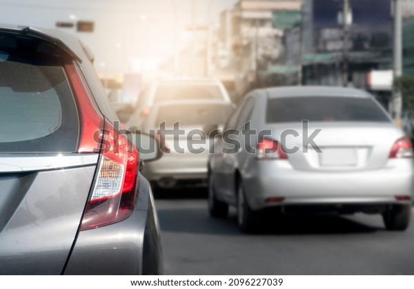Rear side of gray car with turn on brake light on\
the road in traffic junction. Various cars that park in a queue and\
run through a lot.