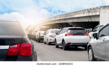 Rear Side View Of Black Car With Turn On Brake Light. Traffic Conditions That Stop In A Queue At Intersections. Blurred View Of A Concrete Bridge Under The Bright Blue Sky.