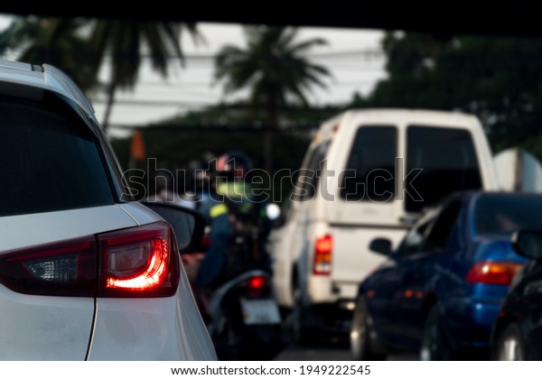 Rear side of white car with open brake light\
on the road with blurred of motorcycle and other car at evening\
time. Environment of upcountry\
communities.