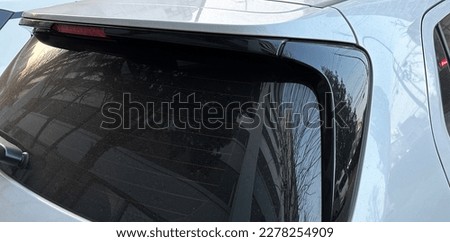 the rear side of a white car and tinted glass back windows
