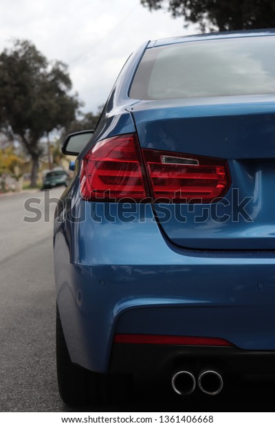 Rear taillight of a blue automotive vehicle parked\
on a street