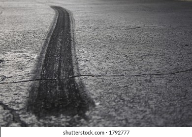 A rear tire burnout or skid mark on old cracked asphalt.