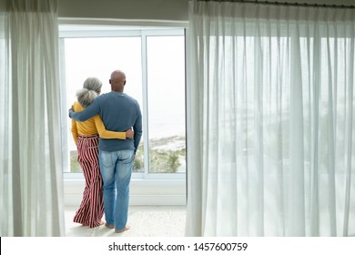 Rear view of active African-american senior couple with arm around standing near window at home - Powered by Shutterstock