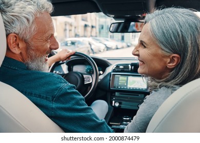 Rear view of active senior couple enjoying car ride while sitting on front seats of the car - Powered by Shutterstock