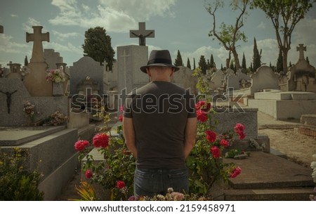 Rear view of adult man mourning in cemetery.