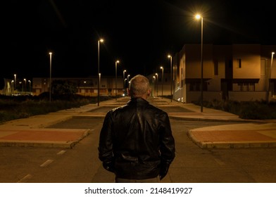 Rear View Of Adult Man Walking On Street At Night