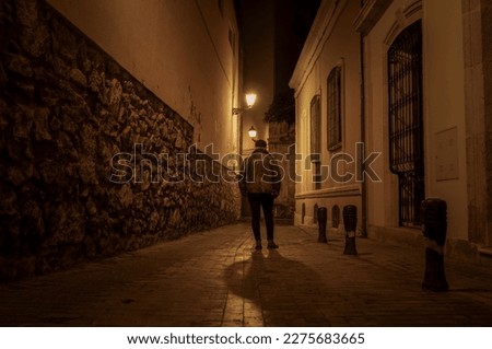 Rear view of adult man walking on street at night. Almeria, Spain