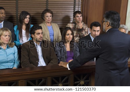 Rear view of a advocate communicating with the jurors in the court house