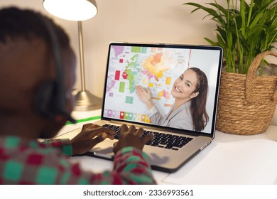 Rear view of a african american boy using laptop having a video call with biracial female teacher. Distant learning online education concept - Powered by Shutterstock