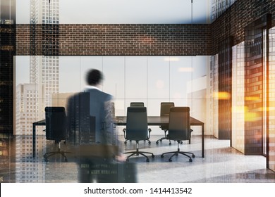Rear view of African American businessman with briefcase entering modern office conference room with white and brick walls and long meeting table. Toned image double exposure blurred