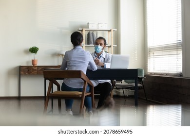 Rear View African American Doctor In Protective Medical Mask Consulting Indian Woman Patient At Meeting In Hospital, Discussing Checkup Results And Symptoms, Healthcare And Coronavirus Concept