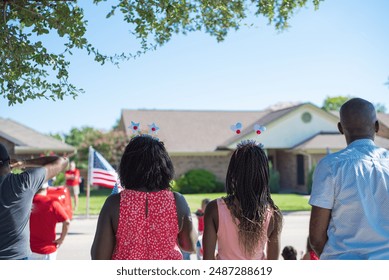 Rear view African American families with hair hoop decoration watching Independence Day parade on residential street on July Fourth freedom celebration in Coppell, Texas, patriotism background. USA - Powered by Shutterstock