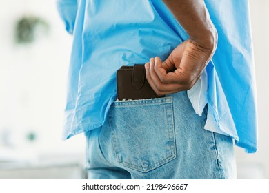 Rear View Of African American Man Keeping Wallet In Back Pocket Of His Jeans, Closeup, Cropped. Black Guy Getting Ready To Go To Work Or To Shop