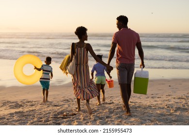 Rear view of african american parents carrying blankets and cooler walking with children at beach. nature, unaltered, beach, childhood, family, togetherness, lifestyle, enjoyment and holiday. - Powered by Shutterstock