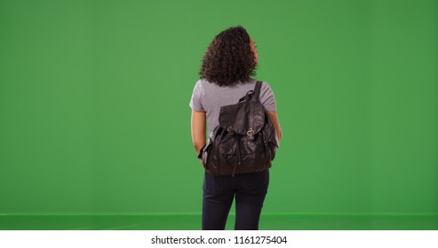 Rear view of African American woman wearing backpack standing on green screen - Powered by Shutterstock