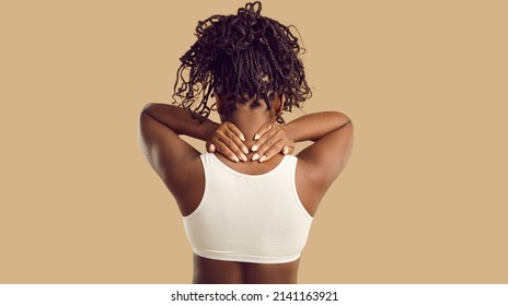 Rear view of African American woman on yellow background struggle with backache. Acute pain in neck concept. Unhealthy girl suffer from back ache or spasm. Sedentary lifestyle problem. - Shutterstock ID 2141163921