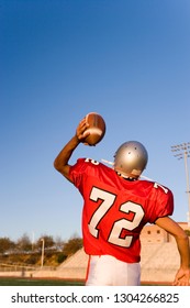 Rear View Of An American High School Quarterback Throwing A Football During A Game