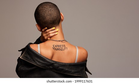 Rear view of anonymous woman with express yourself written on back. Gender fluid woman from behind on grey background.