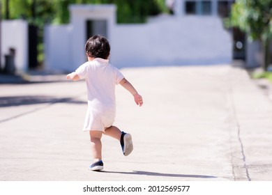 Rear View Of Asian Baby Boy Running On The Road In The Morning. Near His House. Summer Time. Child Aged 1-2 Years Old.