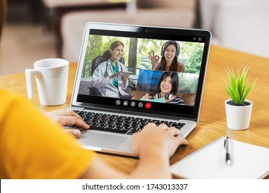 Rear View Of Asian Business Woman Discussing With Doctor And Teamwork Colleague To Follow Up Sickness In Video Conference When Coronavirus Outbreak, Covid-19 Pandemic, Online Meeting And New Normal