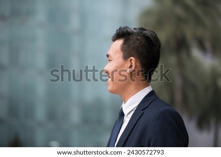 Rear view of an Asian businessman looking away. Chinese business man standing outdoors.
