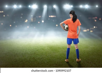 Rear view of asian female footballer with the ball on the field - Powered by Shutterstock