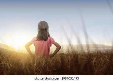 Rear view of Asian girl in an aviator cap standing with a sunset sky background. World Children Day